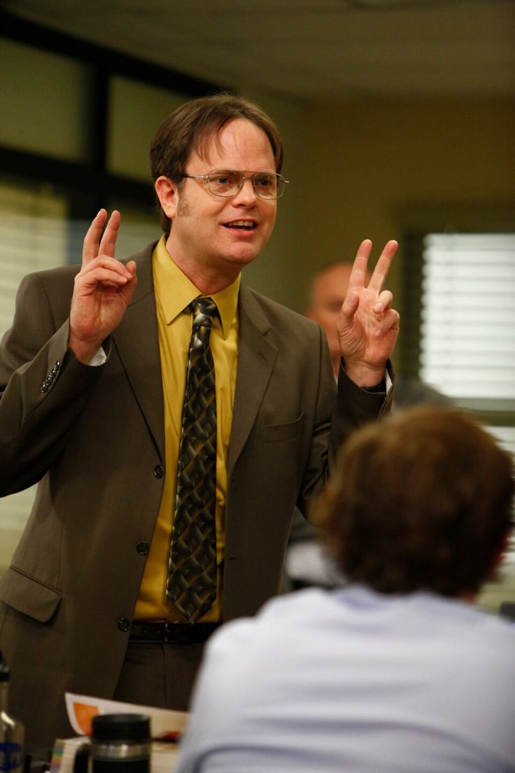 a man in a suit and tie making the v sign with his hands while another person looks on