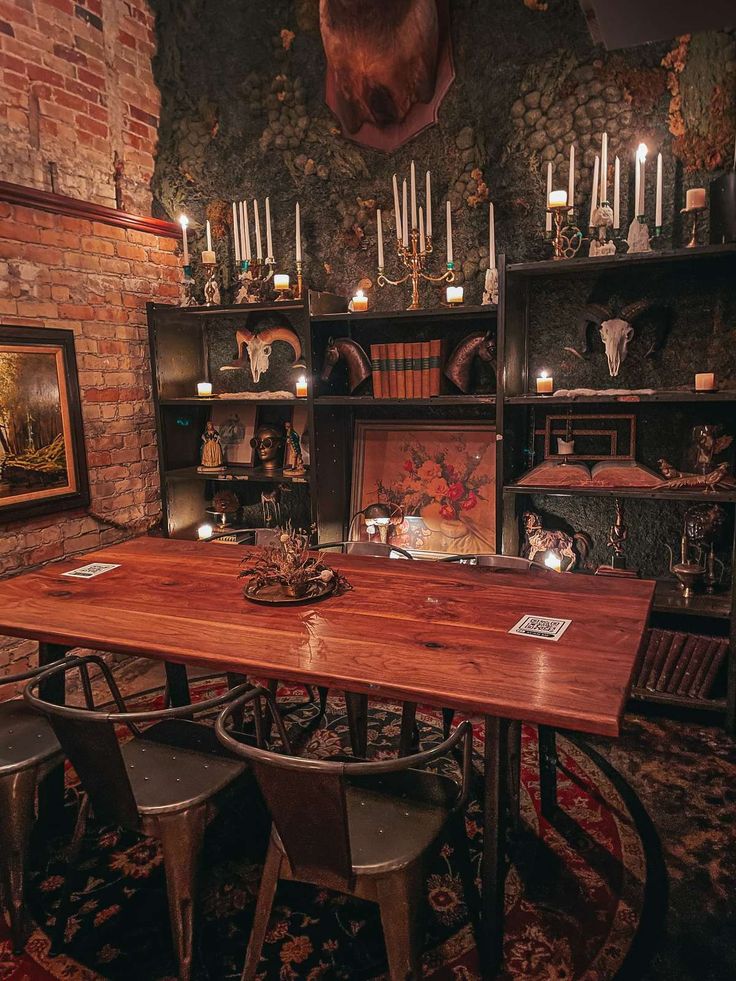 a wooden table surrounded by metal chairs in a room with bookshelves and candles