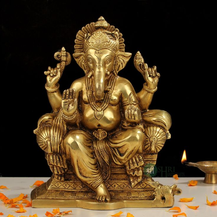 an elephant statue sitting on top of a table next to a candle and some petals