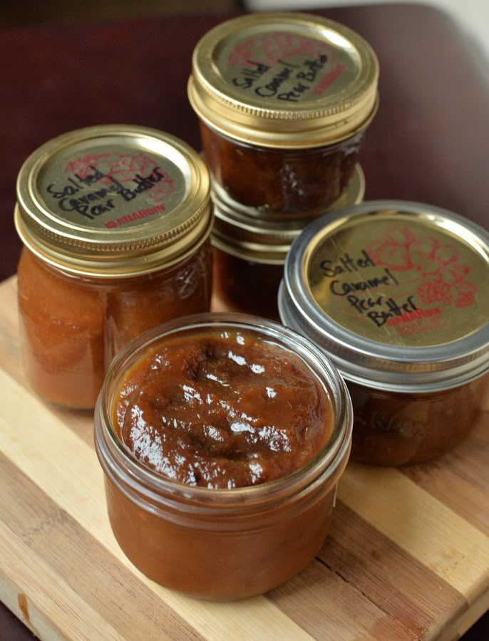 four jars of jam sit on a cutting board