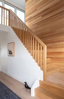 a wooden stair case next to a white wall