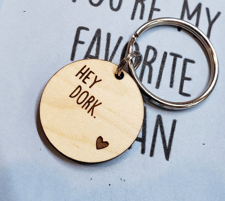 a wooden keychain with the words hey dork on it and a heart