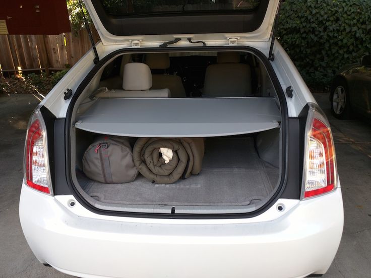 the back end of a white car with its trunk open and two blankets folded on it