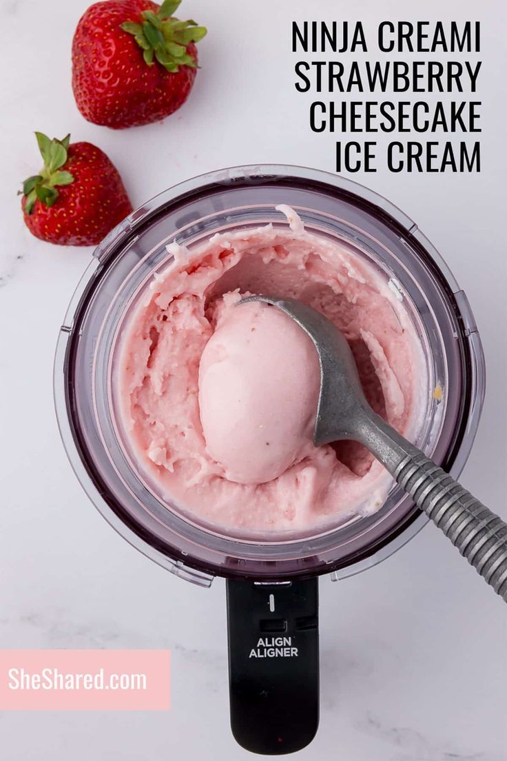 a scoop of ice cream in a blender with strawberries on the side