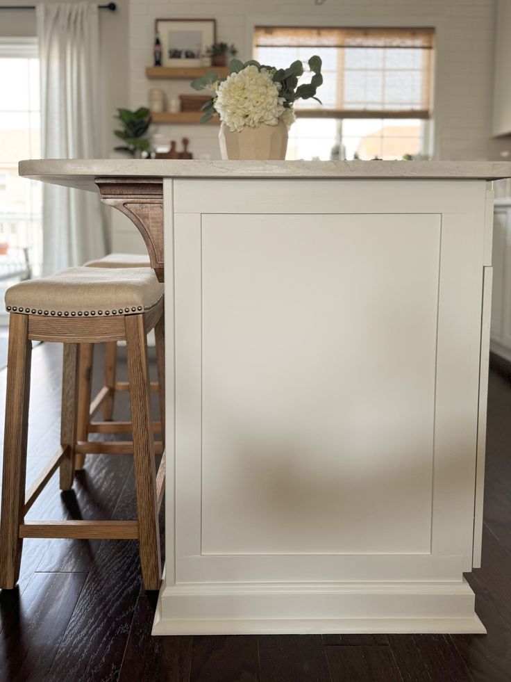 a kitchen island with two stools and a flower pot on it in the center