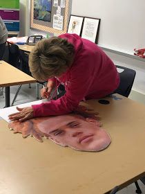 a woman is making a face out of clay on a table in front of other people