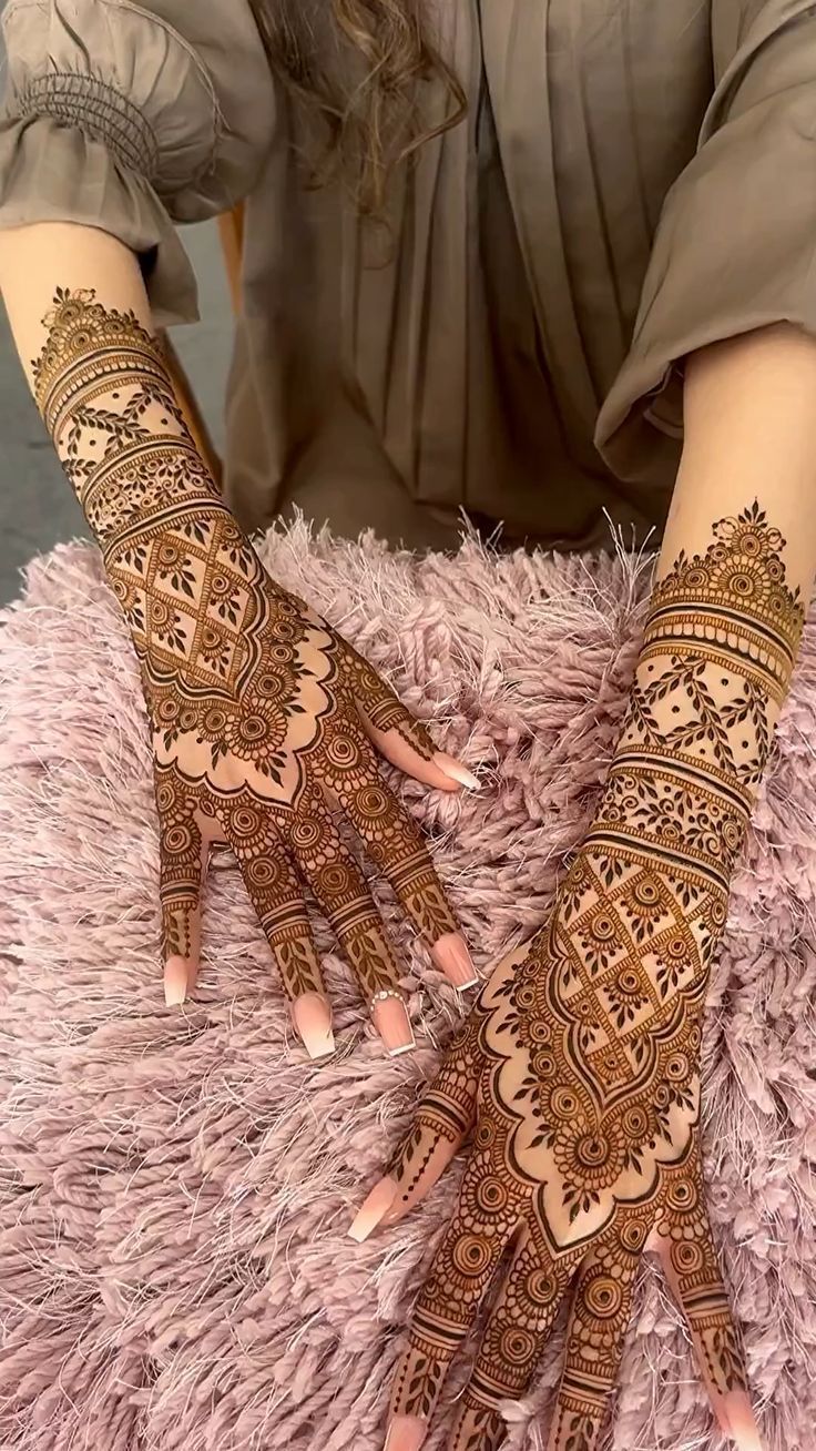 a woman's hands with hennap on them, sitting on a pink rug