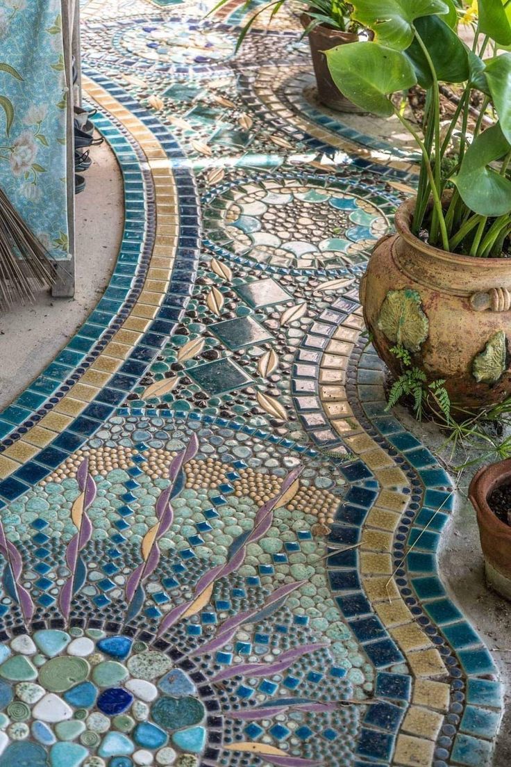 some potted plants are sitting on a mosaic tile floor in front of a house