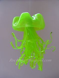 a green jellyfish hanging from a hook in the water with it's mouth open