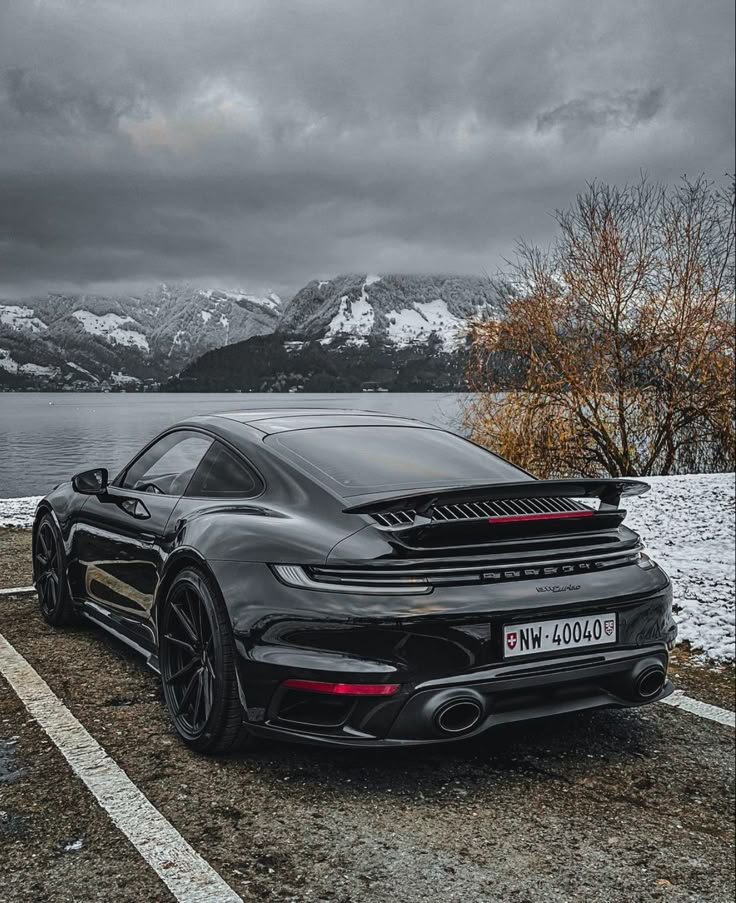 a black sports car parked in front of a lake