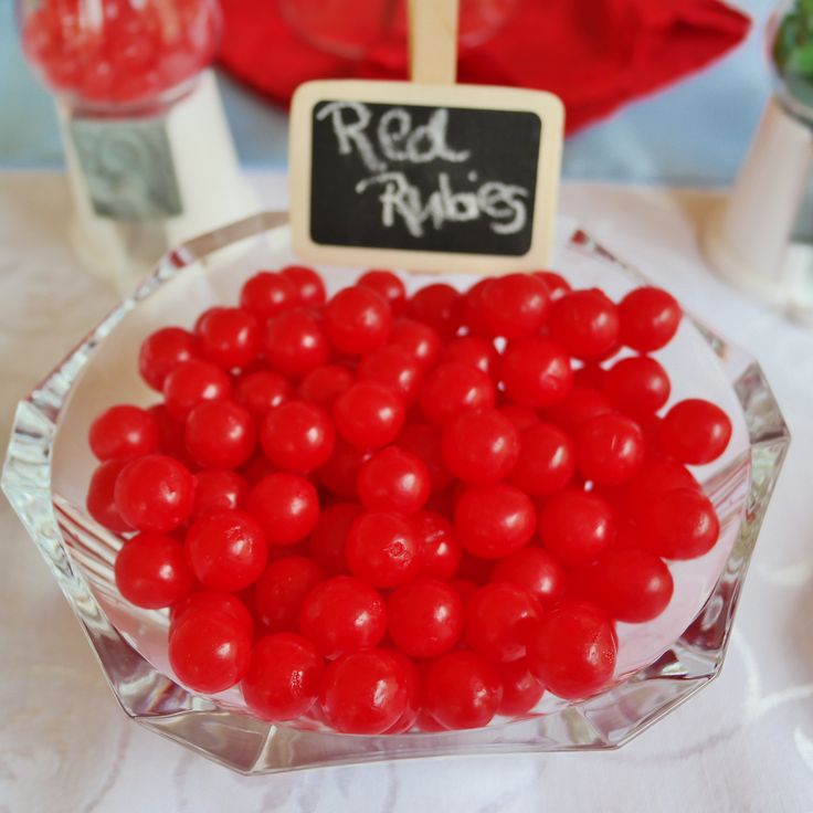 a glass bowl filled with red candies on top of a table