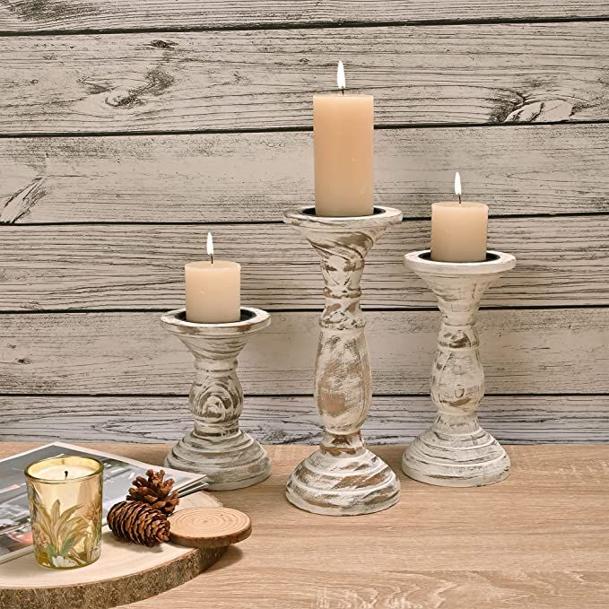 three candles are sitting next to each other on a table with pine cones and decorations