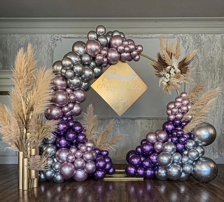 a purple and silver balloon arch with flowers