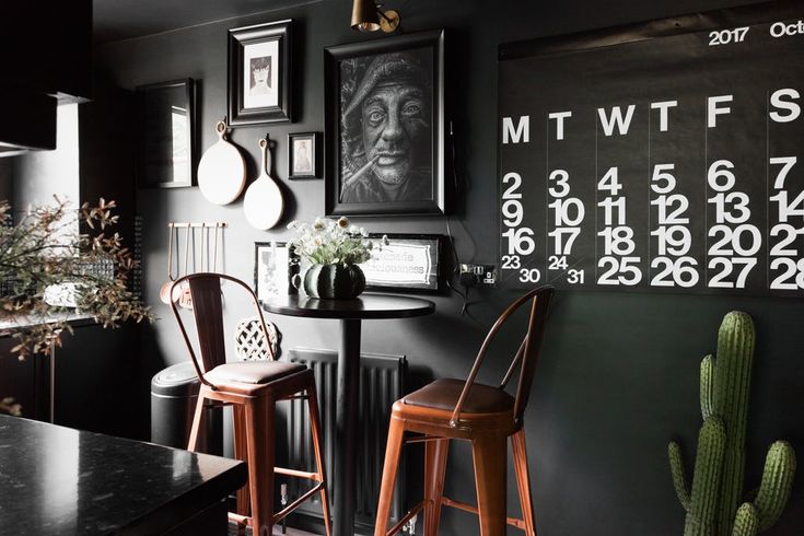 two wooden stools sit in front of a table with a calendar on the wall