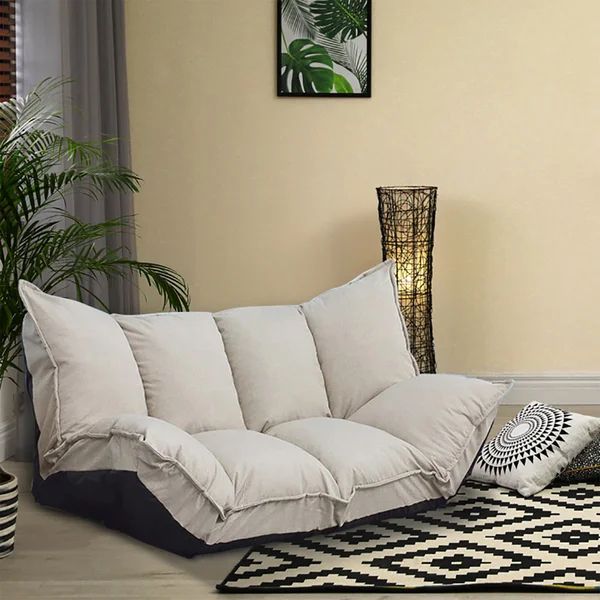 a living room with a couch, rug and potted plant on the side wall