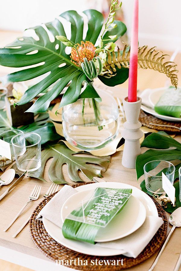 the table is set with green and white plates, silverware, and greenery