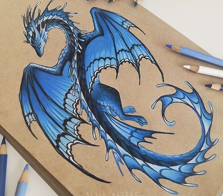 a drawing of a blue dragon sitting on top of a piece of paper next to colored pencils