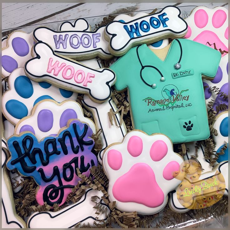 decorated cookies in the shape of paw prints and doctor's shirts with thank you written on them