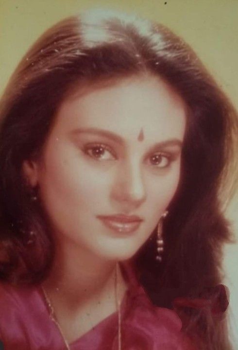 an old photo of a woman with long dark hair and earrings on her head, wearing a red blouse