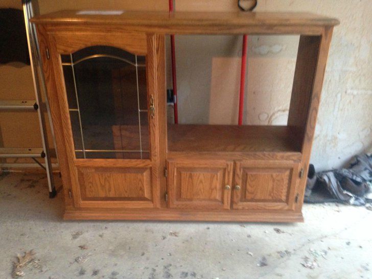 a wooden entertainment center with glass doors and drawers in a room that is being remodeled