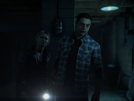 two people standing next to each other in a dark room with one person holding a flashlight