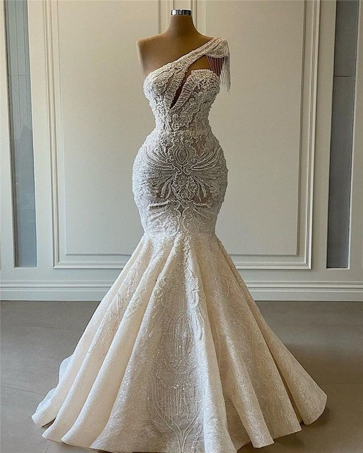 a wedding dress on display in front of a white wall with a mannequin