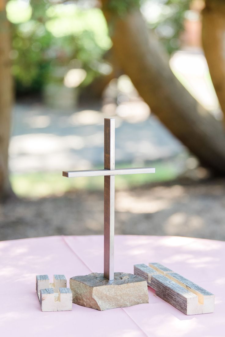 a wooden cross sitting on top of a table next to two blocks of wood and rocks