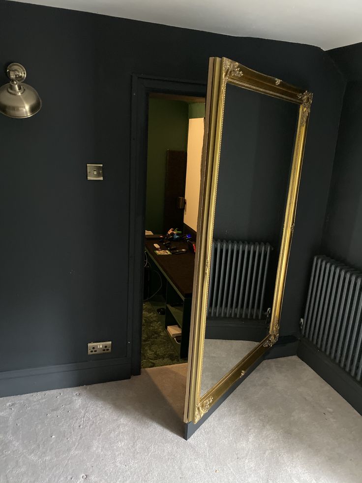 an empty room with a large mirror on the wall and a radiator in the corner