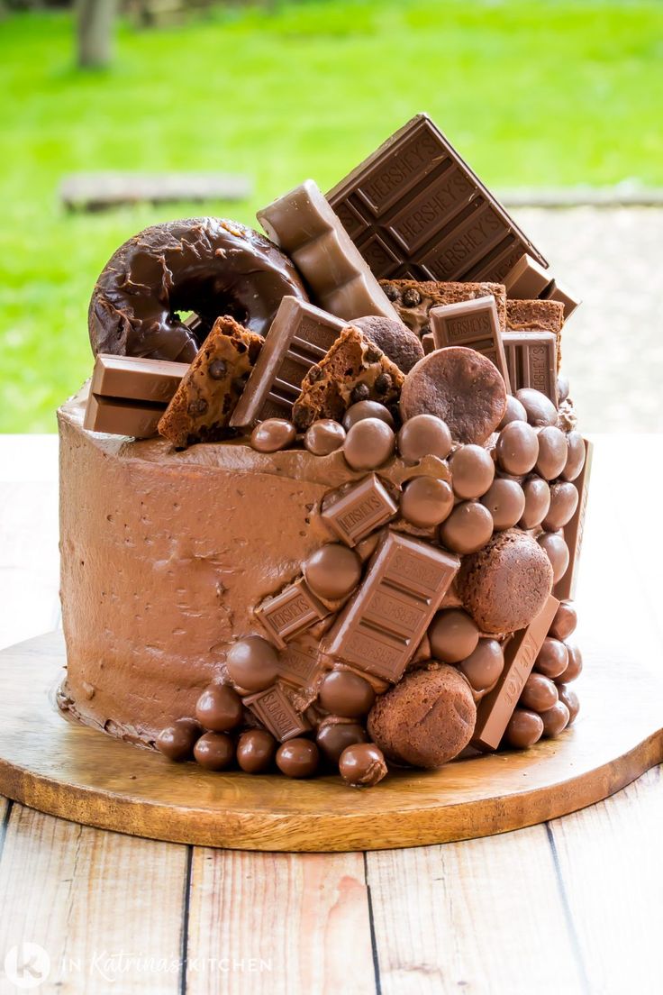 a chocolate cake on a wooden platter with lots of chocolate candies in it