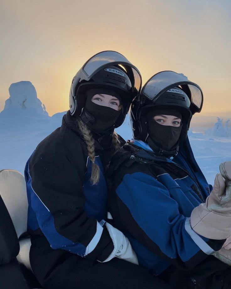 two people sitting in the snow wearing ski gear