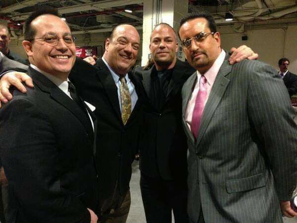 three men in suits and ties posing for a photo with another man wearing a pink tie