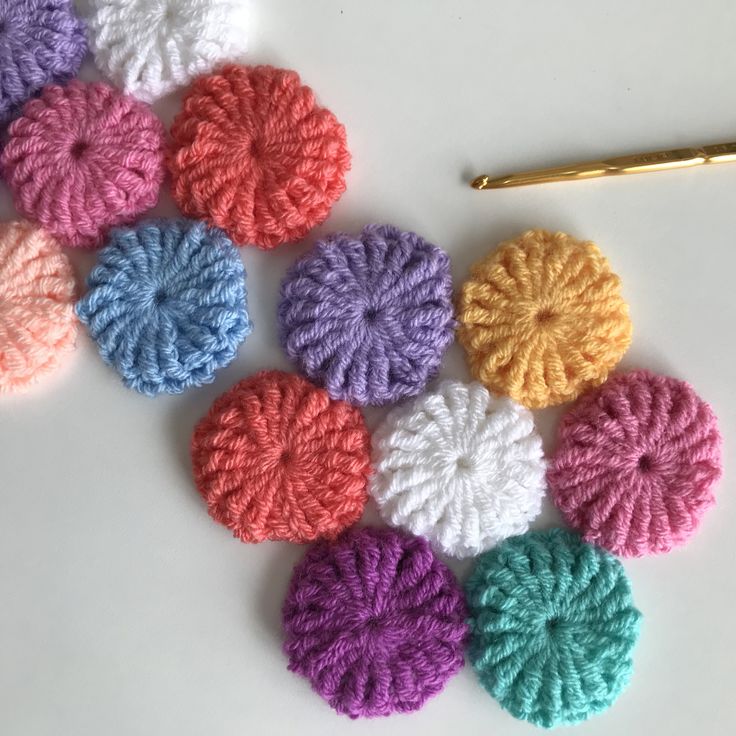 crocheted flowers are arranged on a white surface with a gold pen next to them