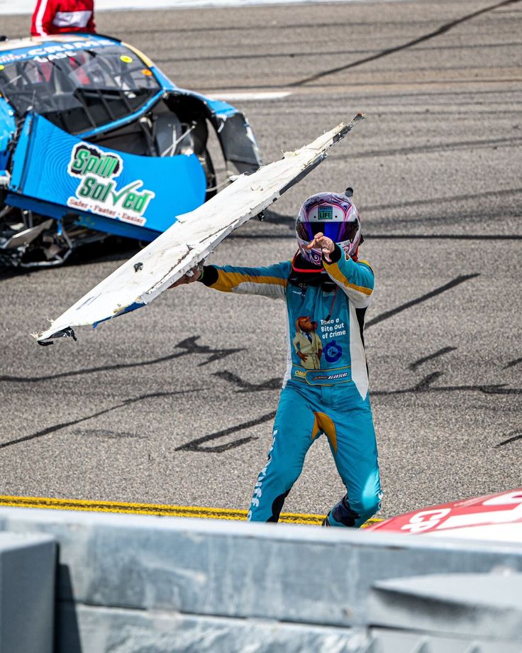 a person with a helmet and goggles holds up a wing