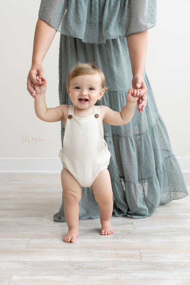 a woman holding the hand of a baby