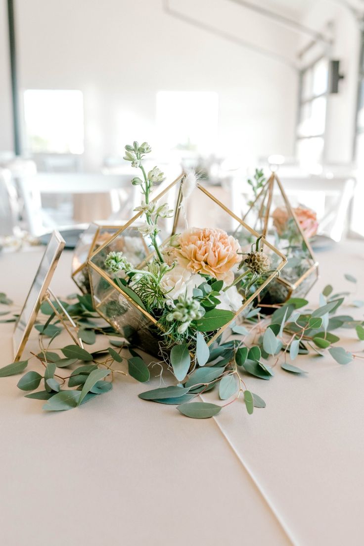 an arrangement of flowers and greenery on a table