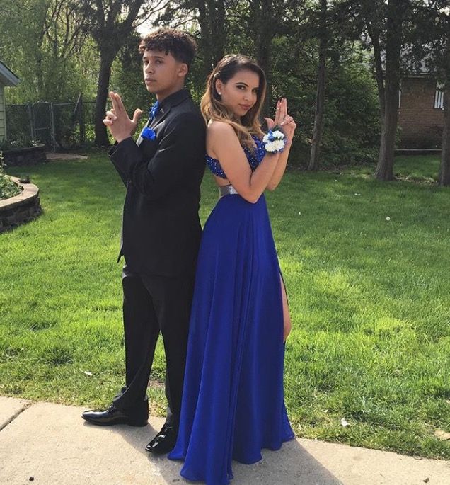 a young man and woman dressed in formal wear posing for the camera with their fingers up