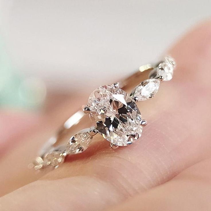 a woman's hand holding an engagement ring with two pear shaped diamonds on it