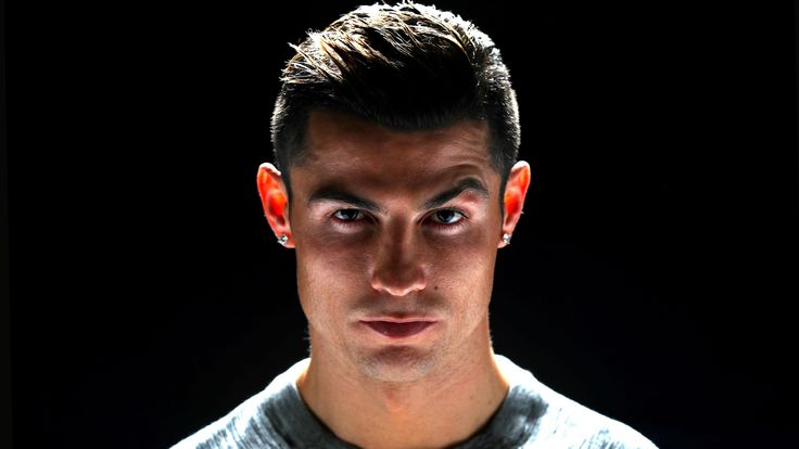 a young man smiling at the camera in front of a black background with his eyes open