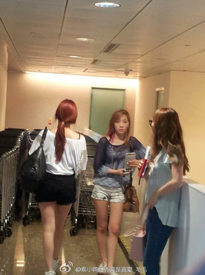 three girls are walking down the hallway in an office building, one is holding a cell phone