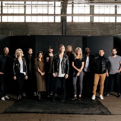 a group of people standing next to each other in front of a black wall with lots of windows