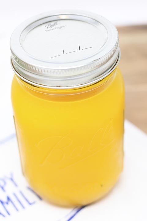 a jar filled with yellow liquid sitting on top of a table