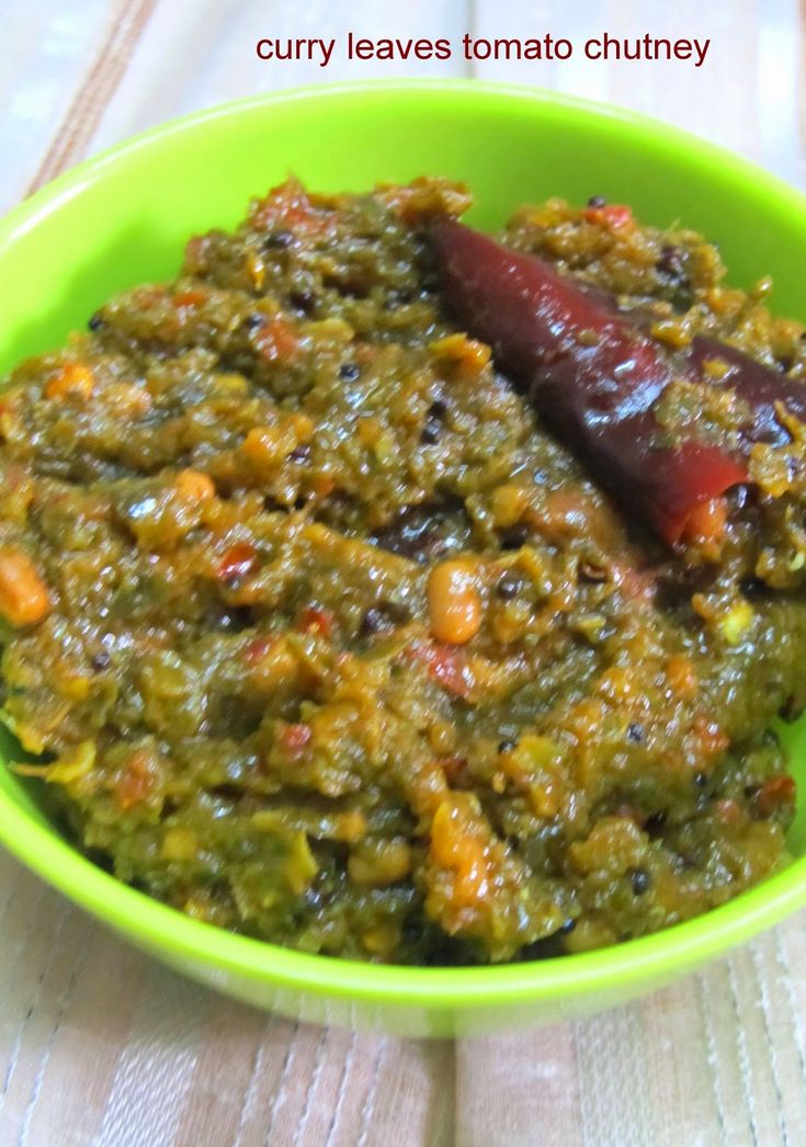 a green bowl filled with food on top of a wooden table