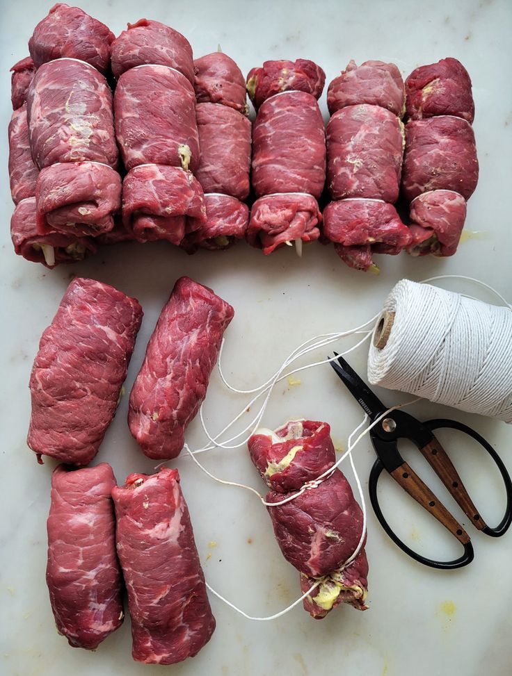 several pieces of raw meat sitting next to a pair of scissors