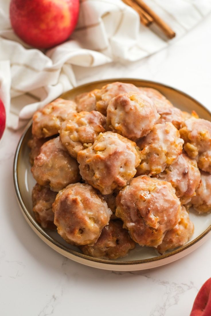 apples and cinnamon donuts on a plate with cinnamon sticks in the background, ready to be eaten