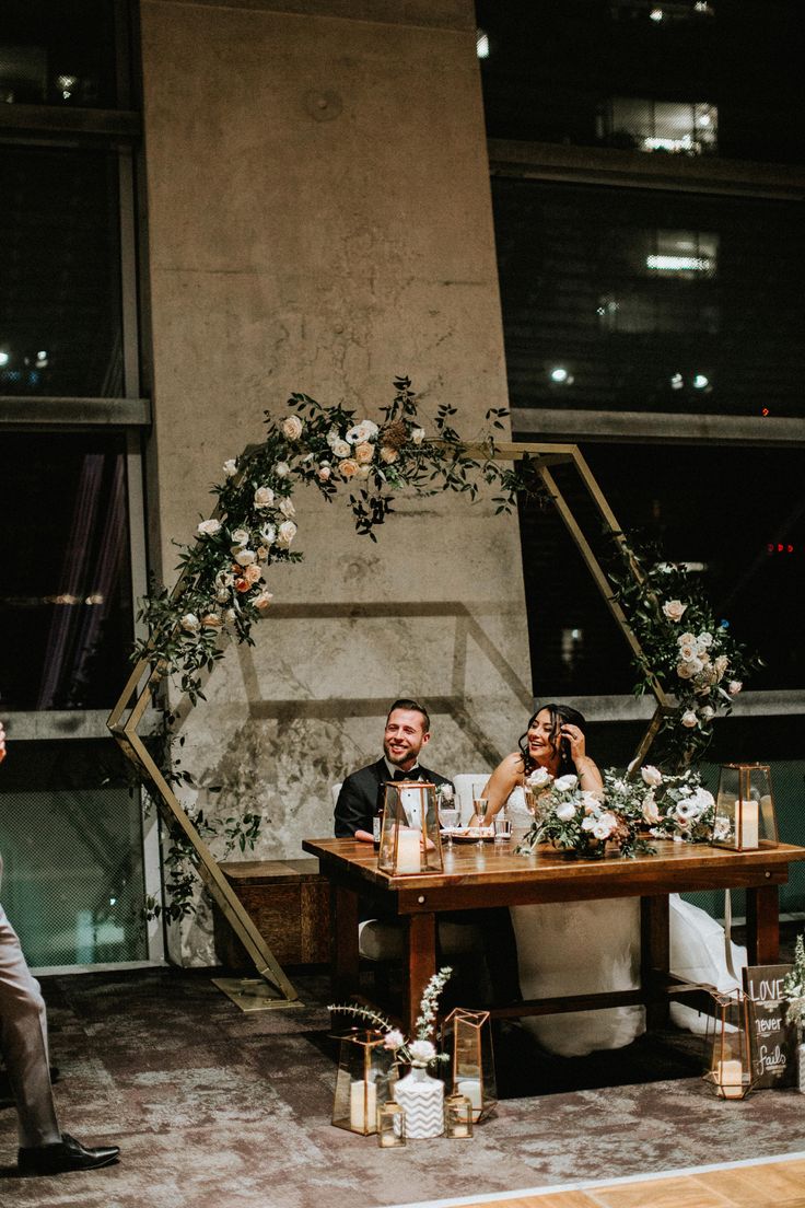 a man and woman sitting at a table with flowers