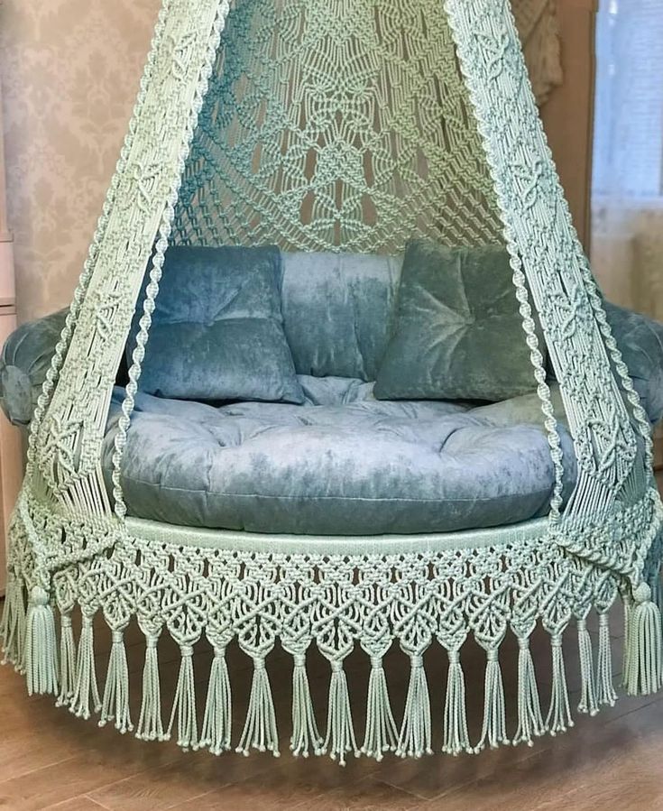 a blue couch sitting inside of a green netted hammock with tassels