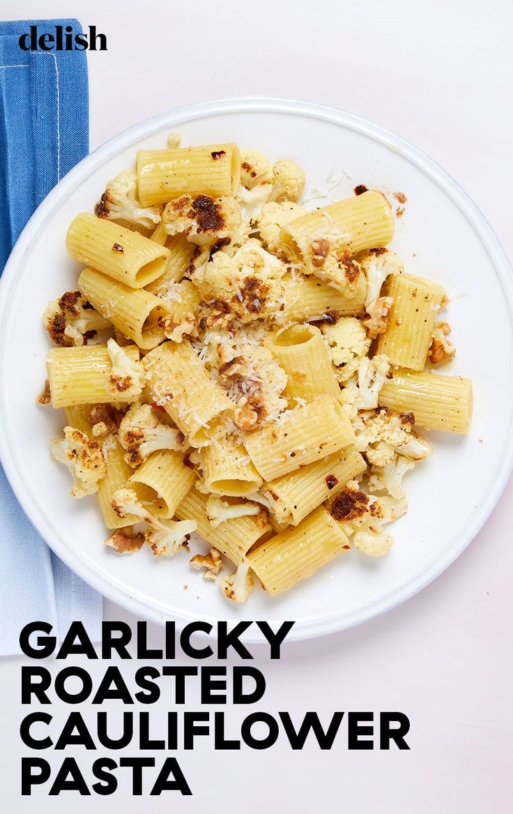 a white plate topped with pasta on top of a blue cloth next to a fork