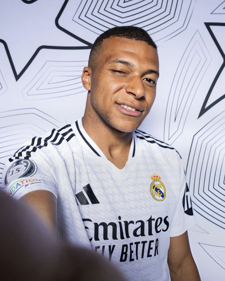 a soccer player is posing for a photo in front of a wall with geometric designs