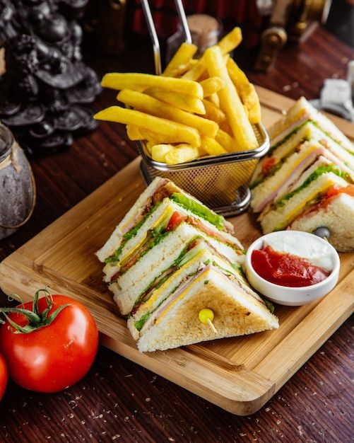 a cut in half sandwich sitting on top of a cutting board next to french fries