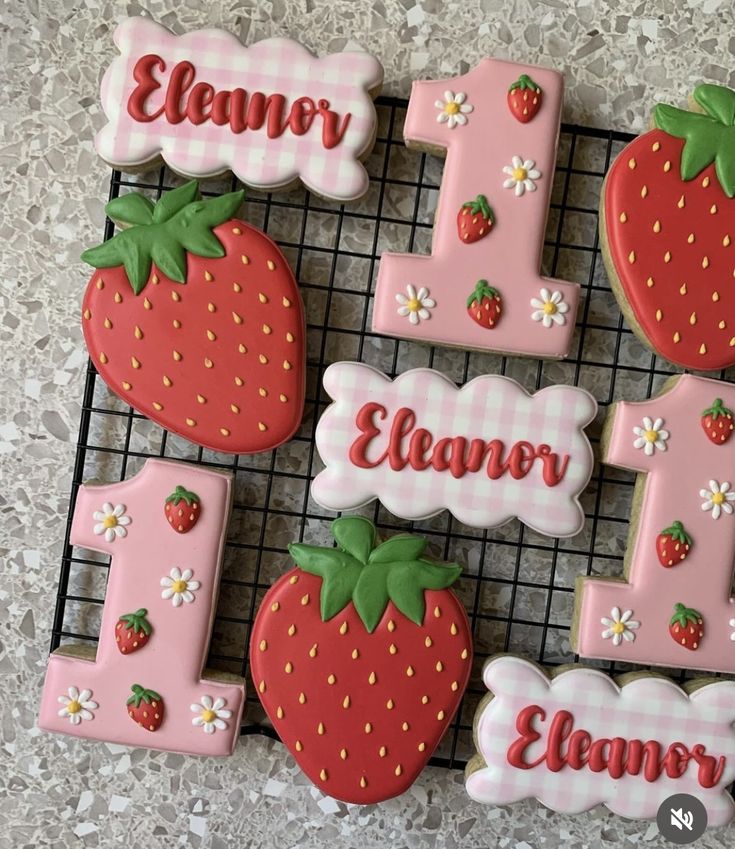 decorated cookies with the number one and strawberrys on them are sitting on a cooling rack